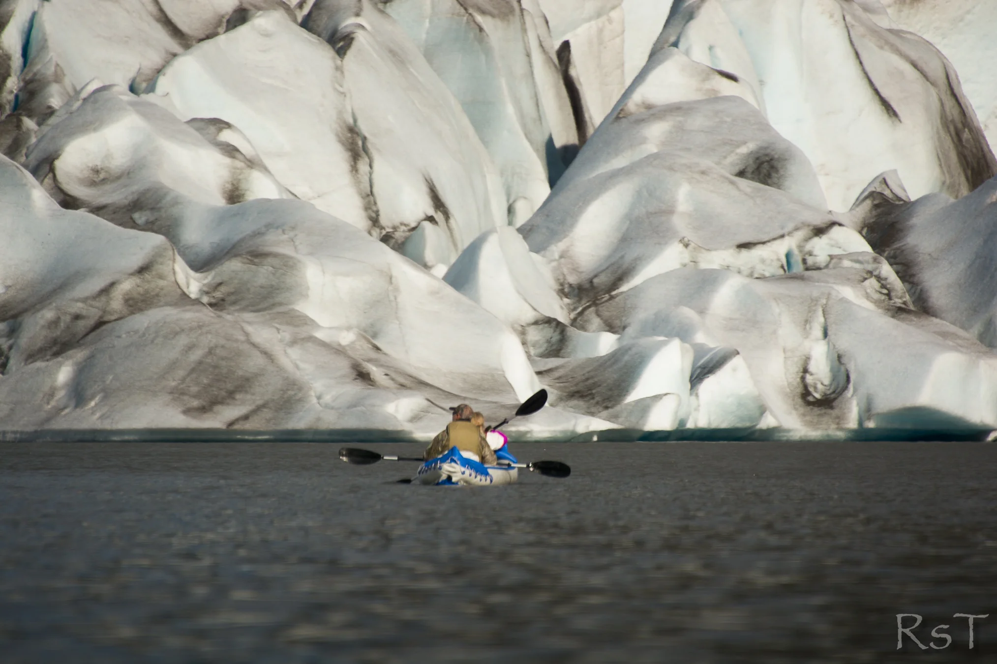people kayaking near a glacier