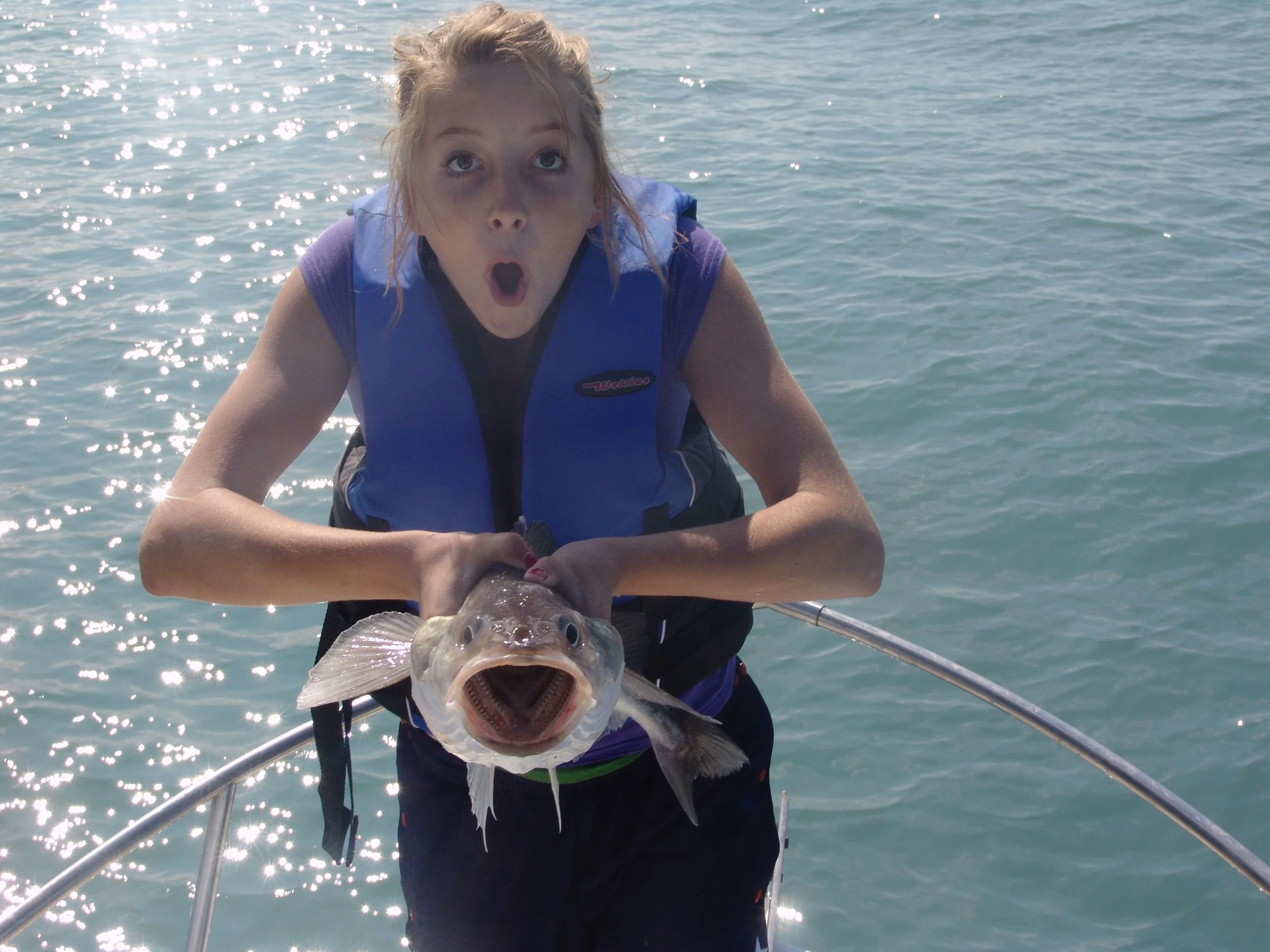 girl making fish face while holding fish